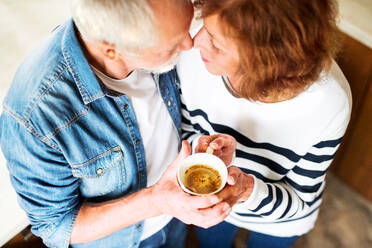 Älteres Ehepaar zu Hause: Ein alter Mann und eine alte Frau im Haus, die eine Tasse Kaffee in der Hand halten. Ansicht von oben. - HPIF25560