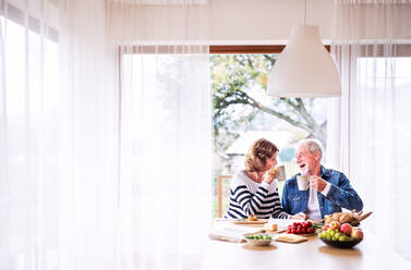 Ein älteres Ehepaar frühstückt zu Hause, ein alter Mann und eine alte Frau sitzen am Tisch und entspannen sich. - HPIF25569