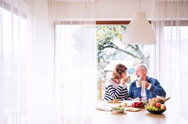 Senior couple eating breakfast at home. An old man and woman sitting at the table, relaxing. - HPIF25569