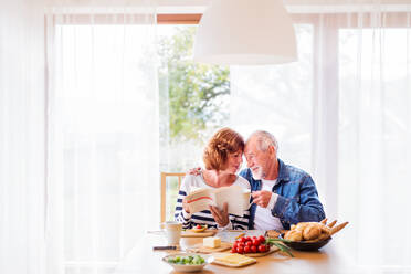 Ein älteres Ehepaar frühstückt zu Hause, ein alter Mann und eine alte Frau sitzen am Tisch und entspannen sich. - HPIF25570