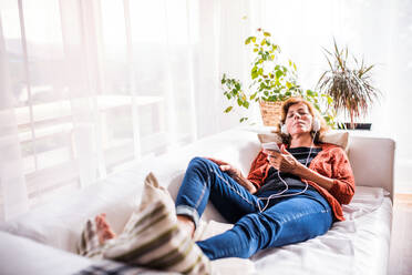 Senior woman relaxing at home, listening to music. - HPIF25579