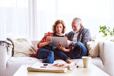 Happy senior couple with tablet relaxing at home. - HPIF25584