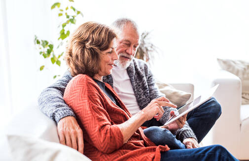 Glückliches Seniorenpaar mit Tablet, das sich zu Hause entspannt. - HPIF25585