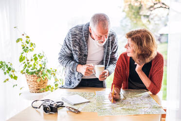 Happy senior couple with map at home, making plans. - HPIF25586