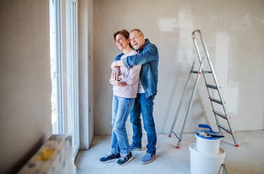 Portrait of cheerful senior couple painting walls in new home, resting. Relocation concept. - HPIF25643