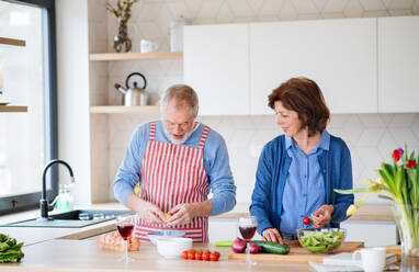 A portrait of happy senior couple indoors at home, cooking. - HPIF25655