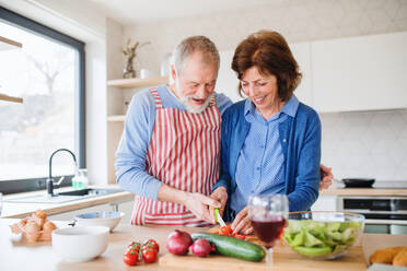 Ein Porträt eines glücklichen, verliebten älteren Paares zu Hause beim Kochen. - HPIF25656
