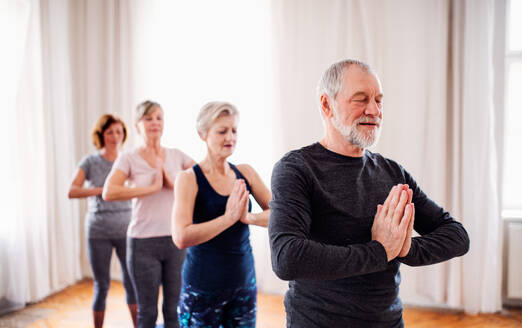 Eine Gruppe aktiver älterer Menschen macht Yoga-Übungen in einem Club im Gemeindezentrum. - HPIF25760