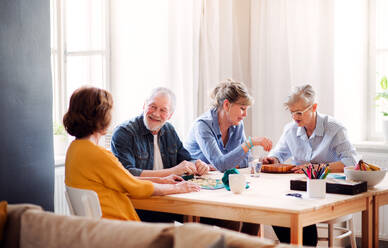Eine Gruppe älterer Menschen sitzt am Tisch im Club des Gemeindezentrums und spielt Brettspiele. - HPIF25775