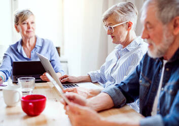 Gruppe älterer Menschen, die Laptops und Tablets in einem Gemeindezentrum benutzen, Konzept der Technologie im täglichen Leben. - HPIF25788