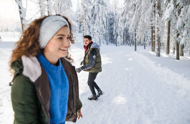 Ein Porträt einer jungen, fröhlichen Frau mit Freunden, die im verschneiten Winterwald stehen. - HPIF25805