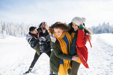 A group of young cheerful friends on a walk outdoors in snow in winter forest, having fun. - HPIF25814