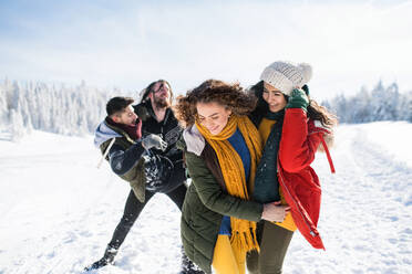 Eine Gruppe junger, fröhlicher Freunde auf einem Spaziergang im Schnee im Winterwald, die Spaß haben. - HPIF25814