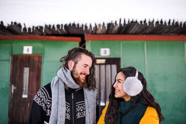 A portrait of young couple standing outdoors in winter, talking. - HPIF25822