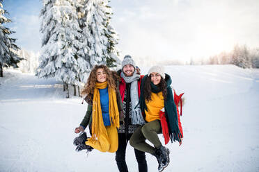 Eine Gruppe fröhlicher junger Freunde, die draußen im Schnee im Winterwald stehen und Spaß haben. - HPIF25826