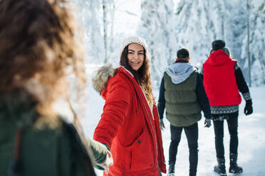 Eine Gruppe junger Freunde auf einem Spaziergang im Schnee im Winterwald, zu Fuß. - HPIF25853