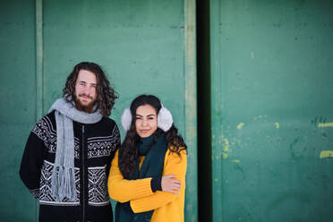 A portrait of young couple standing outdoors in winter, looking at camera. Copy space. - HPIF25884