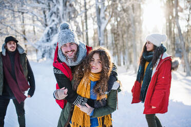 Eine Gruppe junger, fröhlicher Freunde auf einem Spaziergang im Schnee im Winterwald, die Spaß haben. - HPIF25904