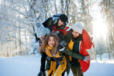 Eine Gruppe junger, fröhlicher Freunde auf einem Spaziergang im Schnee im Winterwald, die Spaß haben. - HPIF25905