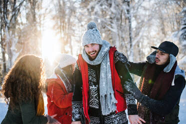 Eine Gruppe junger, fröhlicher Freunde auf einem Spaziergang im Schnee im Winterwald, die Spaß haben. - HPIF25911