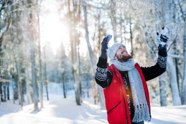 Cheerful young man having fun in snow outdoors in winter. Copy space. - HPIF25915