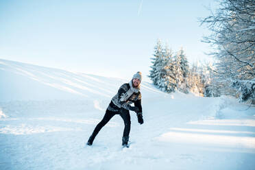 Fröhlicher junger Mann, der im Winter draußen im Schnee Spaß hat. - HPIF25922