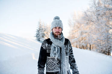 Portrait of young man standing in snow nature outdoors in winter, looking at camera. - HPIF25924