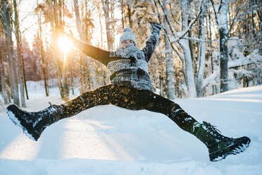 Junger Mann, der sich im Winter im Freien vergnügt und im Schnee springt. - HPIF25926