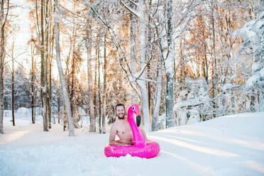 Ein Porträt von oben ohne jungen Mann im Freien im Schnee im Winter Wald, Spaß haben. - HPIF25934