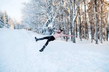 Ein Porträt von oben ohne jungen Mann im Freien im Schnee im Winter Wald, Spaß haben. - HPIF25938