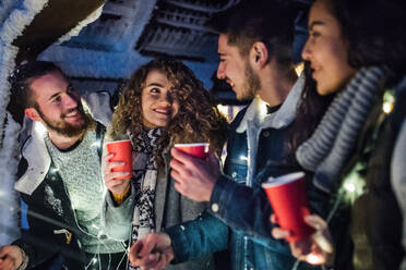 Eine Gruppe junger Freunde, die nachts im Schnee unterwegs sind und Wunderkerzen halten. - HPIF25945