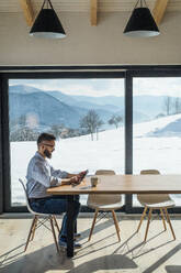 A mature man sitting at the table in new home, using tablet. Copy space. - HPIF25984