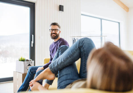 Ein junges, glückliches Paar sitzt auf dem Sofa und zieht in ein neues Haus ein. - HPIF26007