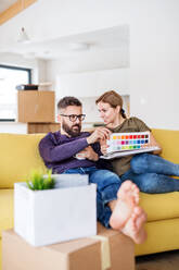 A young couple with color samples sitting on sofa, moving in new home and talking. - HPIF26013