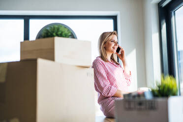 A happy young woman with smartphone moving in new home, making a phone call. - HPIF26025