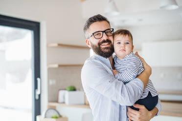 A portrait of mature father with a toddler girl standing indoors. - HPIF26050