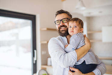 A portrait of mature father holding a toddler girl indoors, hugging. - HPIF26051