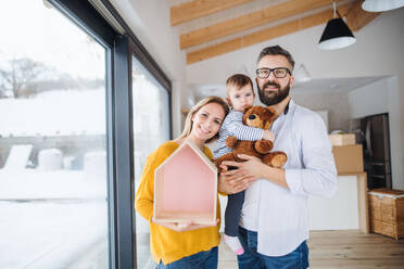 Ein Porträt einer glücklichen jungen Familie mit einem kleinen Mädchen, das in ein neues Haus einzieht. - HPIF26053