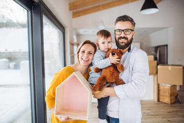 Ein Porträt einer glücklichen jungen Familie mit einem kleinen Mädchen, das in ein neues Haus einzieht. - HPIF26054