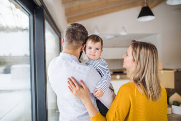 Ein Porträt einer glücklichen jungen Familie mit einem kleinen Mädchen, das in ein neues Haus einzieht. - HPIF26055