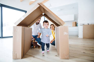 Ein Porträt einer glücklichen jungen Familie mit einem kleinen Mädchen, das in ein neues Haus einzieht. - HPIF26057