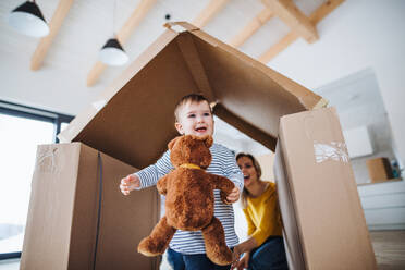 Ein Porträt einer glücklichen jungen Familie mit einem kleinen Mädchen, das in ein neues Haus einzieht. - HPIF26058