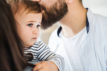 Ein Mittelteil einer jungen Familie mit einem kleinen Mädchen, das zu Hause steht, in Großaufnahme. - HPIF26063