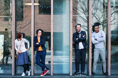 Group of young businesspeople standing outdoors in courtyard, arms crossed. A start-up concept. - HPIF26091