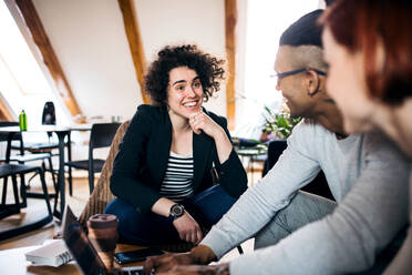 Eine Gruppe junger Geschäftsleute, die einen Laptop im Büro benutzen, Start-up-Konzept. - HPIF26108