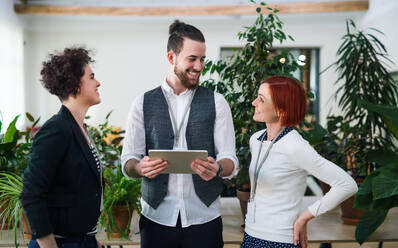 Eine Gruppe junger Geschäftsleute, die ein Tablet im Büro benutzen, ein Start-up-Konzept. - HPIF26127