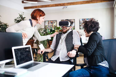 A group of young businesspeople with VR goggles talking in office, start-up concept. - HPIF26135