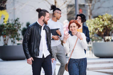 Group of young businesspeople walking outdoors in courtyard, talking. A start-up concept. - HPIF26166