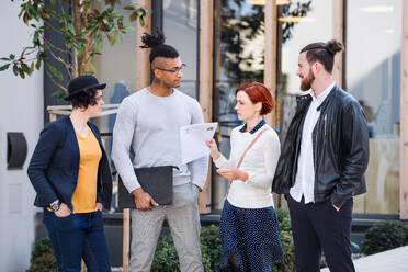 Group of young businesspeople standing outdoors in courtyard, talking. A start-up concept. - HPIF26168