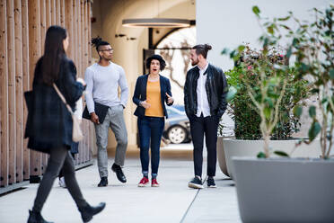 Group of young businesspeople walking outdoors in courtyard, talking. A start-up concept. - HPIF26169